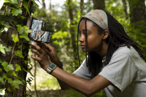 Forestry undergraduate student Lavendar Harris adjusts a trail camera in the Oconee Forest Park.