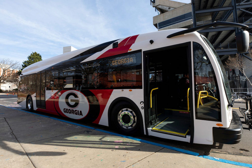 A photo of one of the first electric buses at the bus stop at Tate Plaza across from Sanford Stadium on central campus.