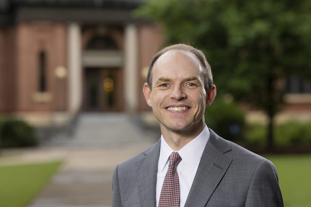 Environmental portrait of Nathan Moore, Assistant to the President, in front of the Administration Building on north campus.