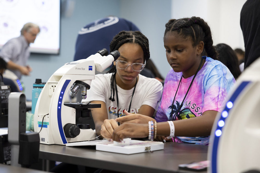 CCSD students Natalie Hight, left, and Celeste Beaton work together with slides at a microscope during the Mini-Med Camp at the Medical Partnership. (Photo by Andrew Davis Tucker/UGA)