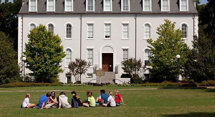 students sitting on lawn infront of Moore Hall on UGA's Campus
